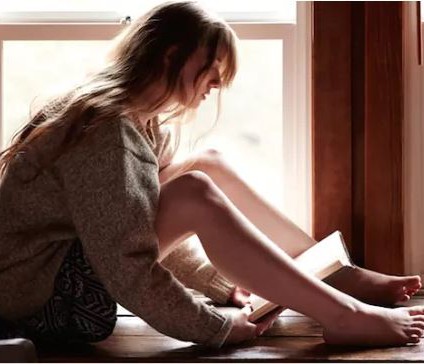 Woman reading a book in a window.