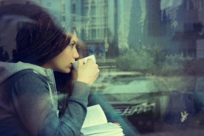 Woman reading and drinking coffee in a cafe.